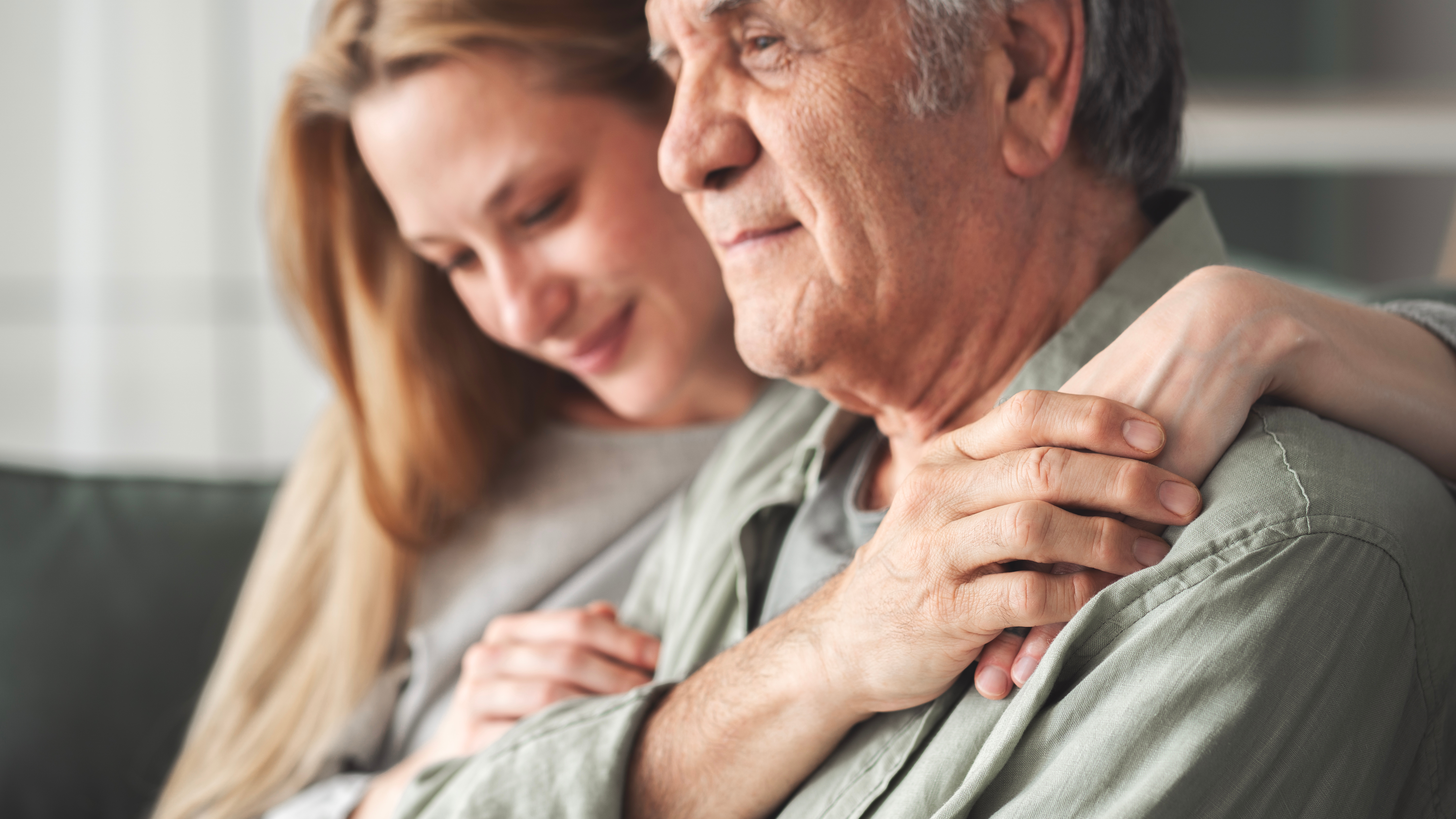 Tochter umarmt ihren an Demenz erkrankten Vater. 