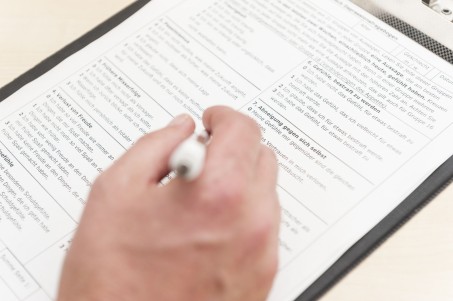 Aufnahmebogen liegt unterhalb einer Hand, die einen Stift hält. Foto: Matthias Jung